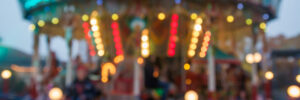 A blurry colorful carousel in the amusement park at evening illumination. The effect of bokeh.